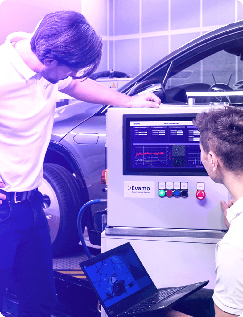Two engineers looking at the deepfluid oil device infront of a car.